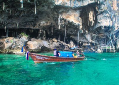 A famosa Viking Cave em Phi Phi, Tailândia com um barquinho longtail na água cristalina